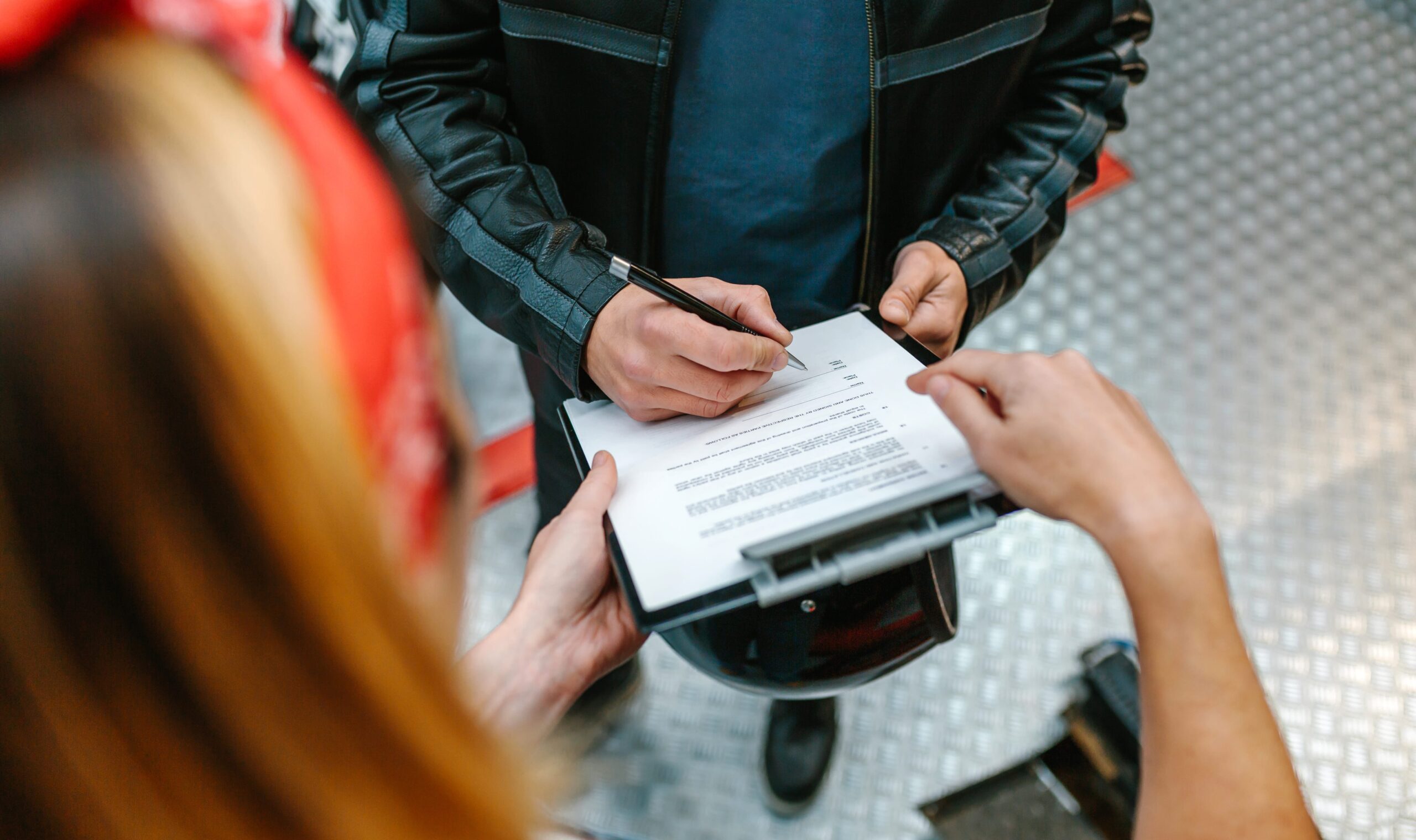 Female holding document while biker signs truck accident claim form