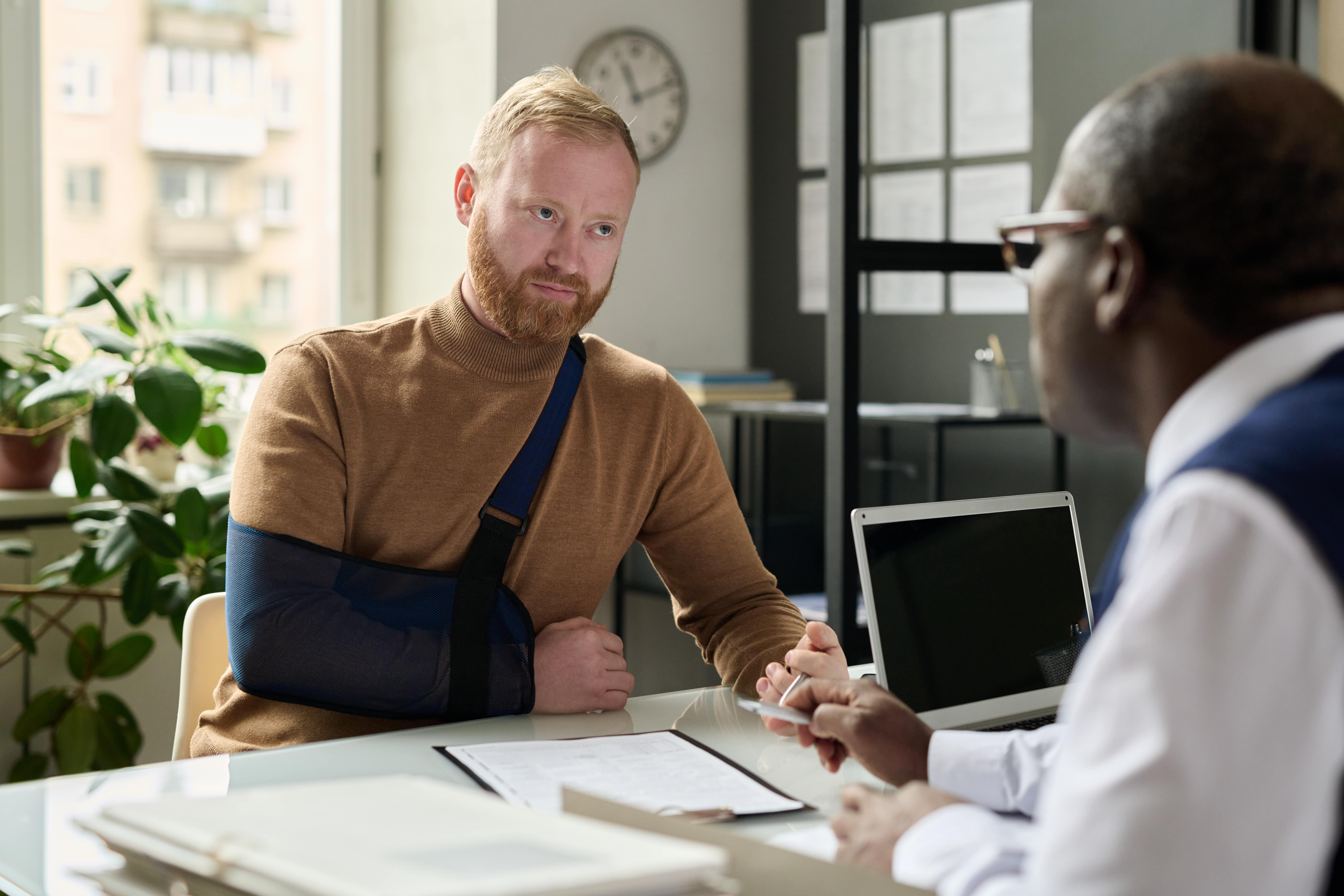 A man speaking with an insurance broker after a motorcycle accident, representing the process of filing a claim and seeking compensation.