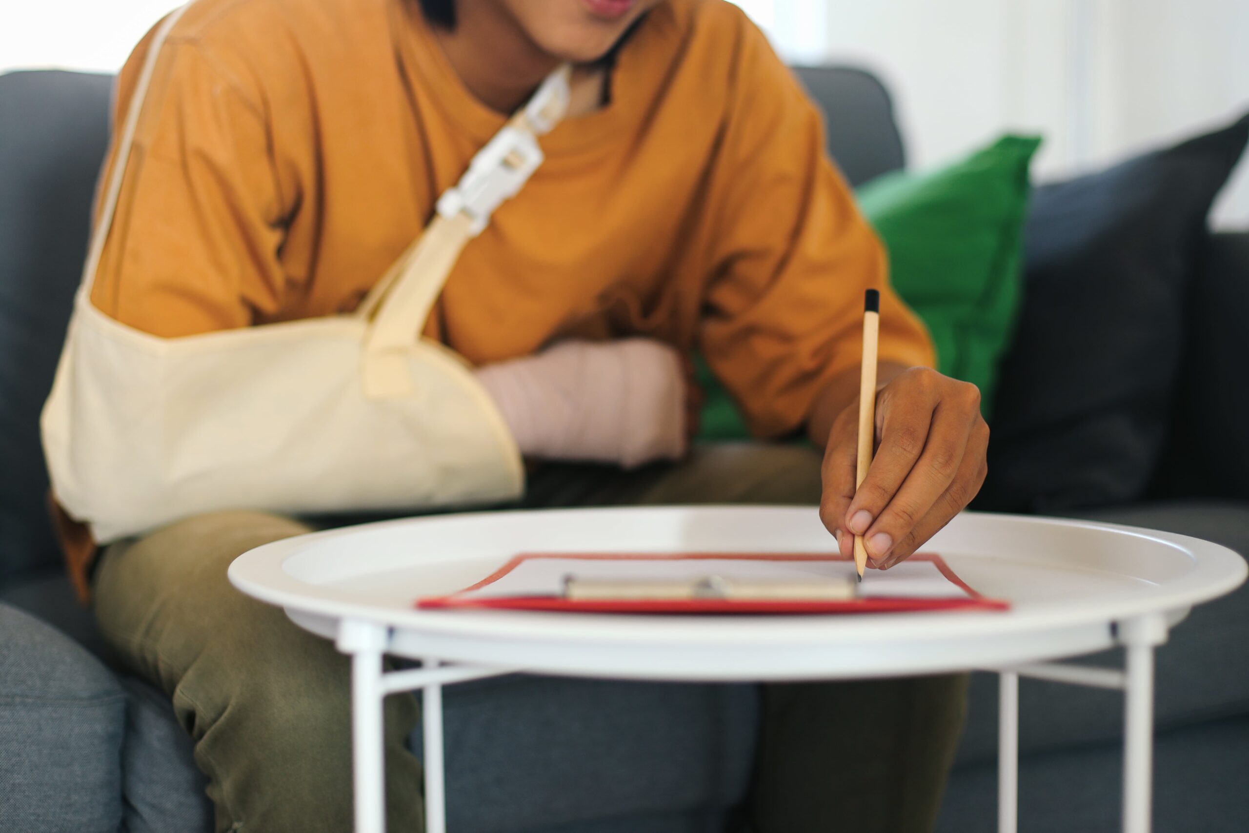 Man with arm sling bandage signing legal documents after a motorcycle accident, representing the legal process of filing a lawsuit.