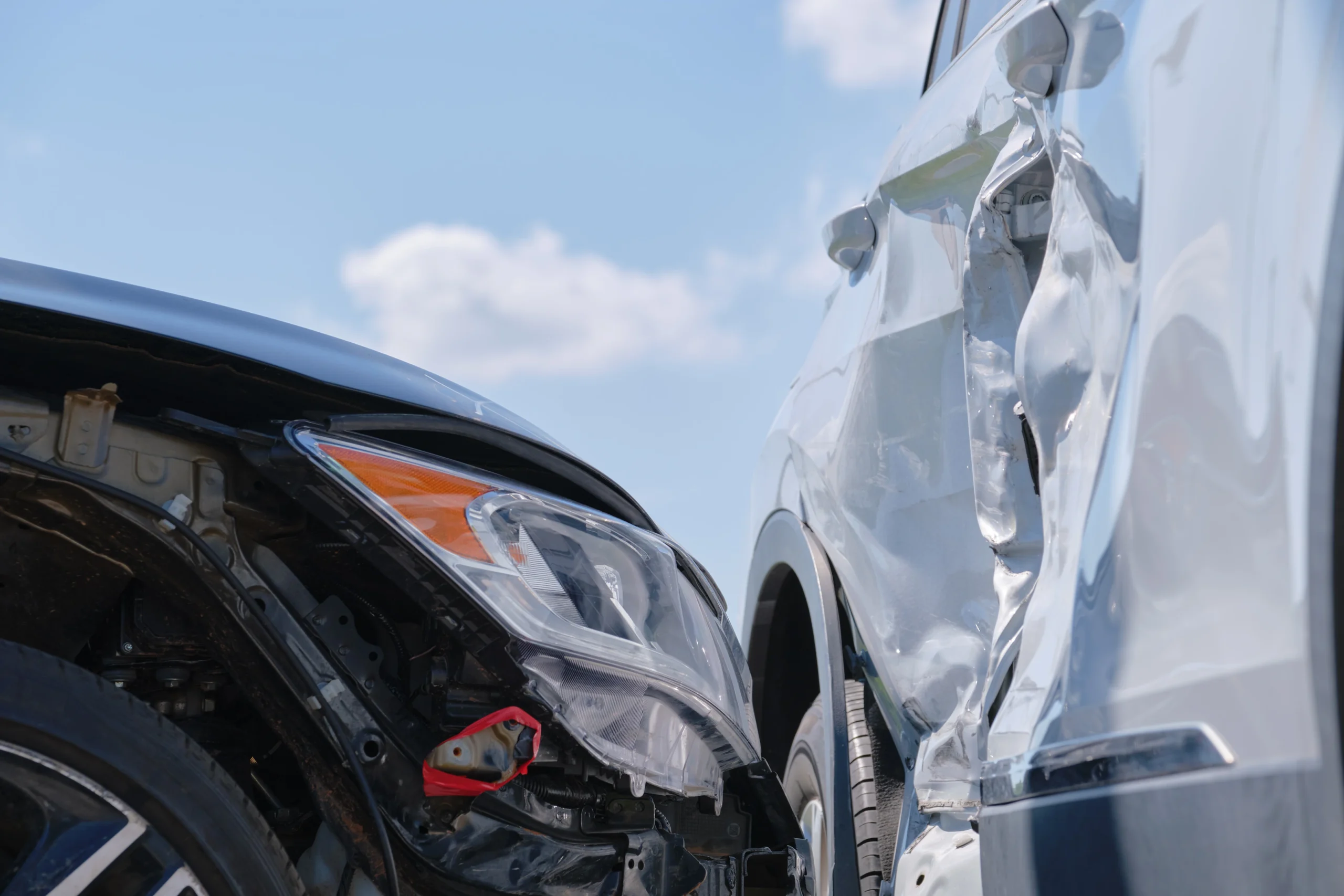 A black car with front-end damage after colliding with a white car on a clear day—highlighting how fault is determined in accidents.